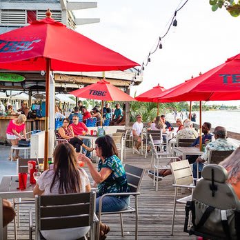Outdoor waterfront restaurant just steps from the property offers vibrant dining and social atmosphere under bright red umbrellas.