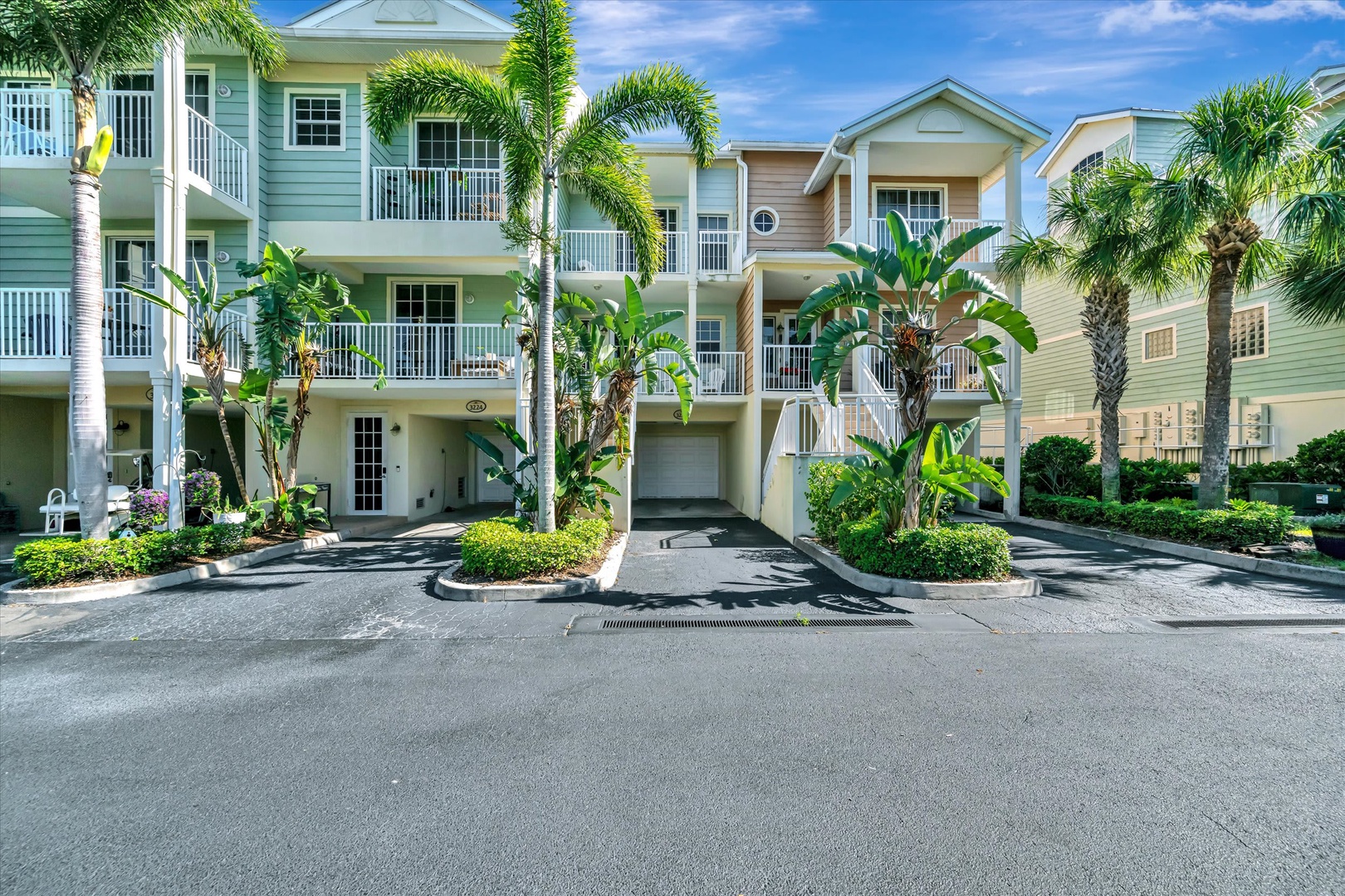 Bright coastal architecture nestled among swaying palms and lush tropical landscaping. This welcoming property features ground-level parking and resort-style balconies throughout the community.