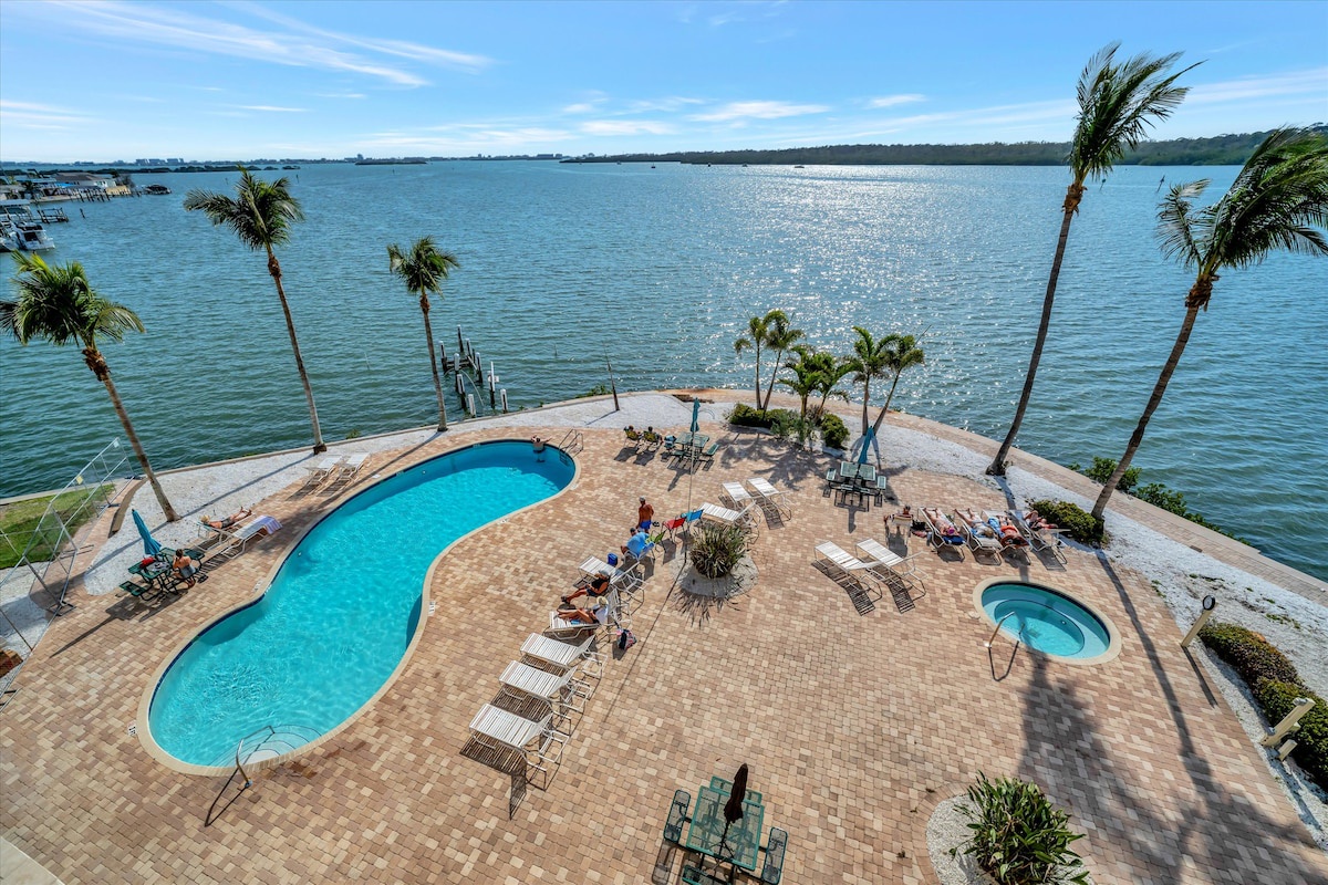 A stunning aerial view of the waterfront pool deck, where sparkling waters meet swaying palms and endless bay vistas create your perfect tropical escape.