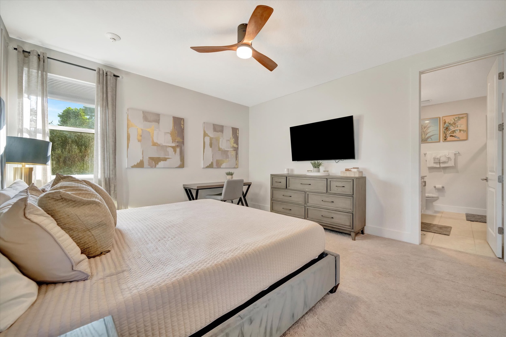Sink into your plush bed in this serene bedroom where a soft ceiling fan keeps you cool, and your own bathroom awaits just steps away for ultimate convenience.