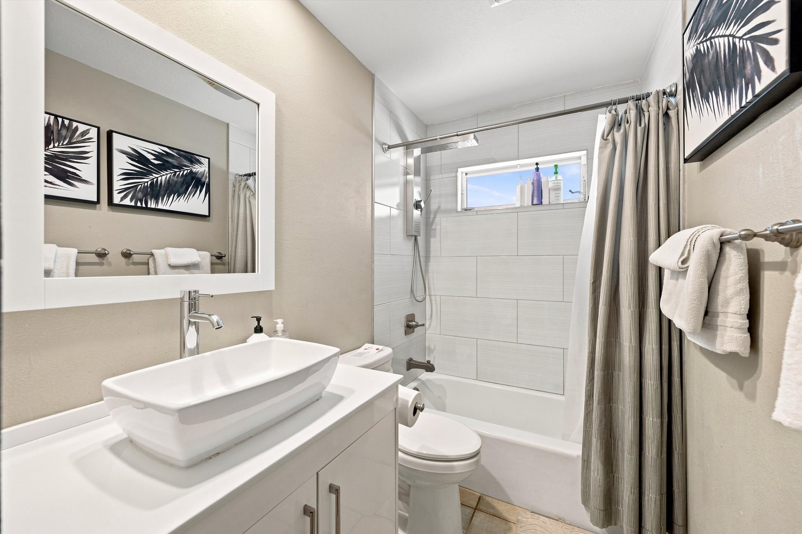 Step into your private spa-like retreat with a modern tub-shower combo and fresh white linens. The crisp tile, bright natural light, and coastal-inspired touches create the perfect space to unwind after a day of exploring.