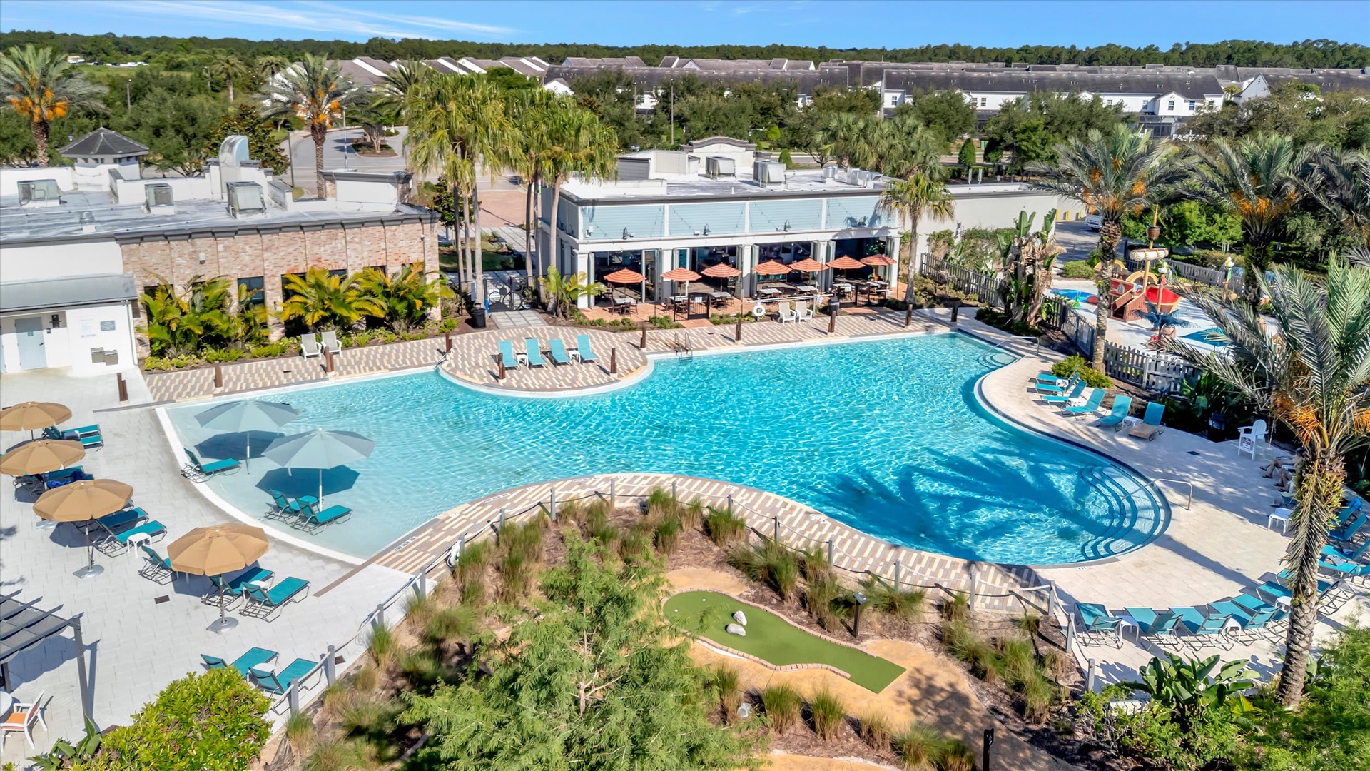 The community features a resort-style lagoon pool with a tiki bar, surrounded by palm trees and lush landscaping in a serene Florida setting.