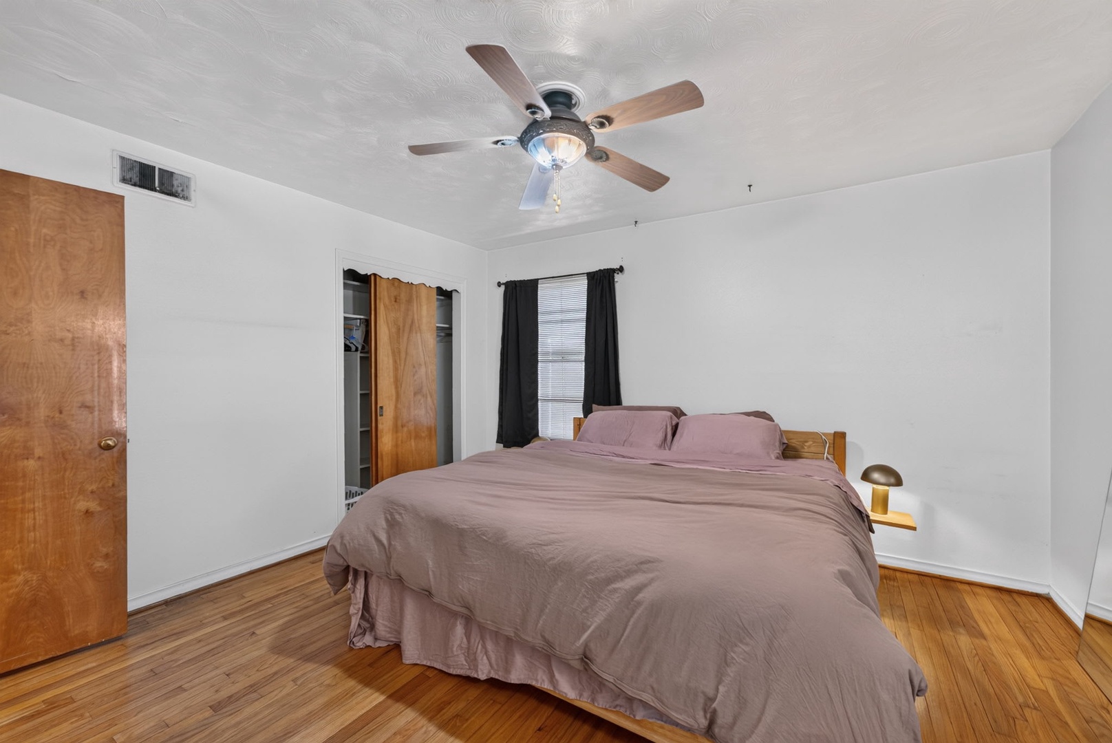 Relax in this bright, spacious bedroom with polished wood floors and a ceiling fan to keep you comfortable year-round.