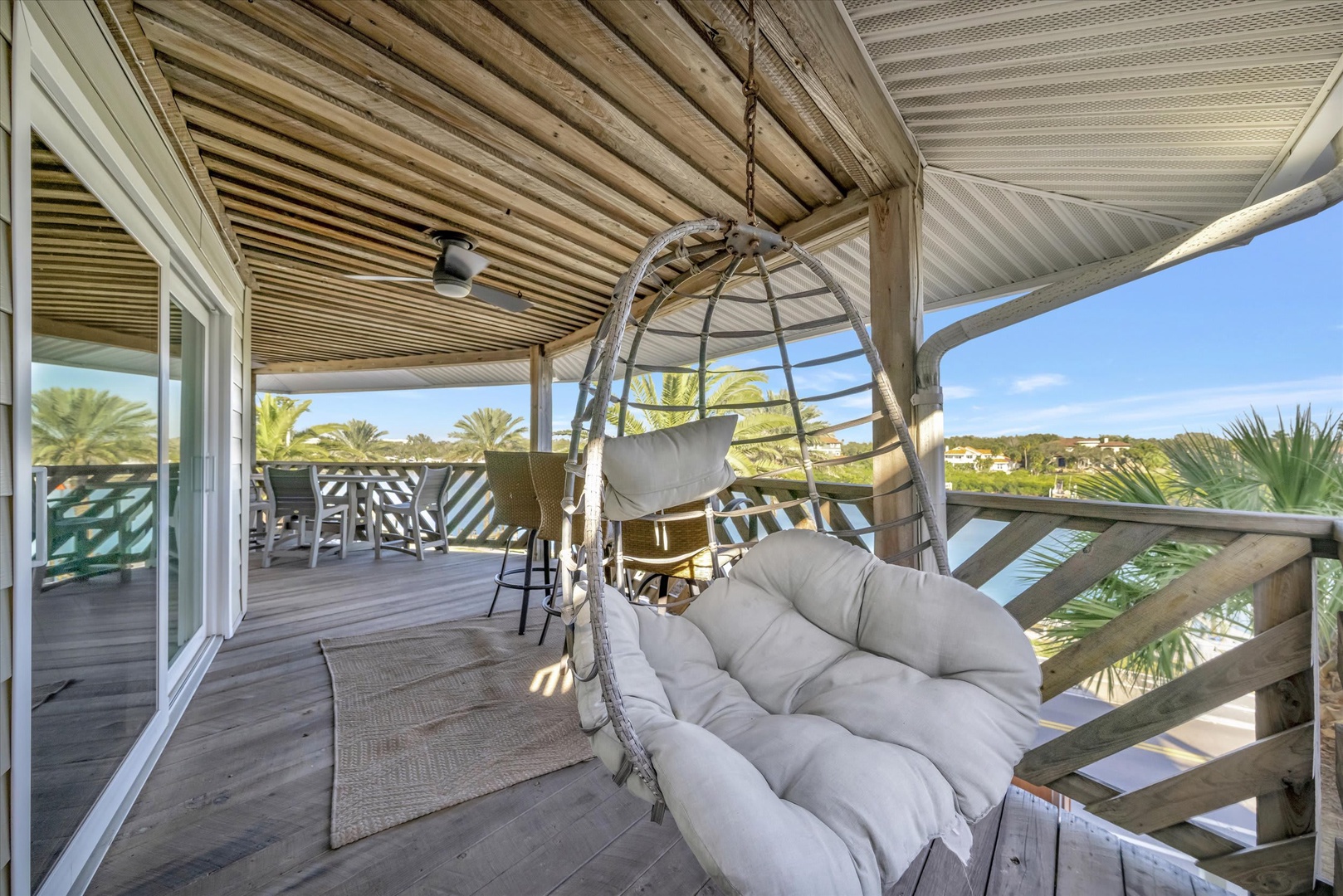 Imagine yourself swaying gently in this hanging chair, surrounded by palm breezes and sweeping views. This covered deck invites you to unwind in style, with cozy seating and a peaceful setting perfect for morning coffee or sunset cocktails.
