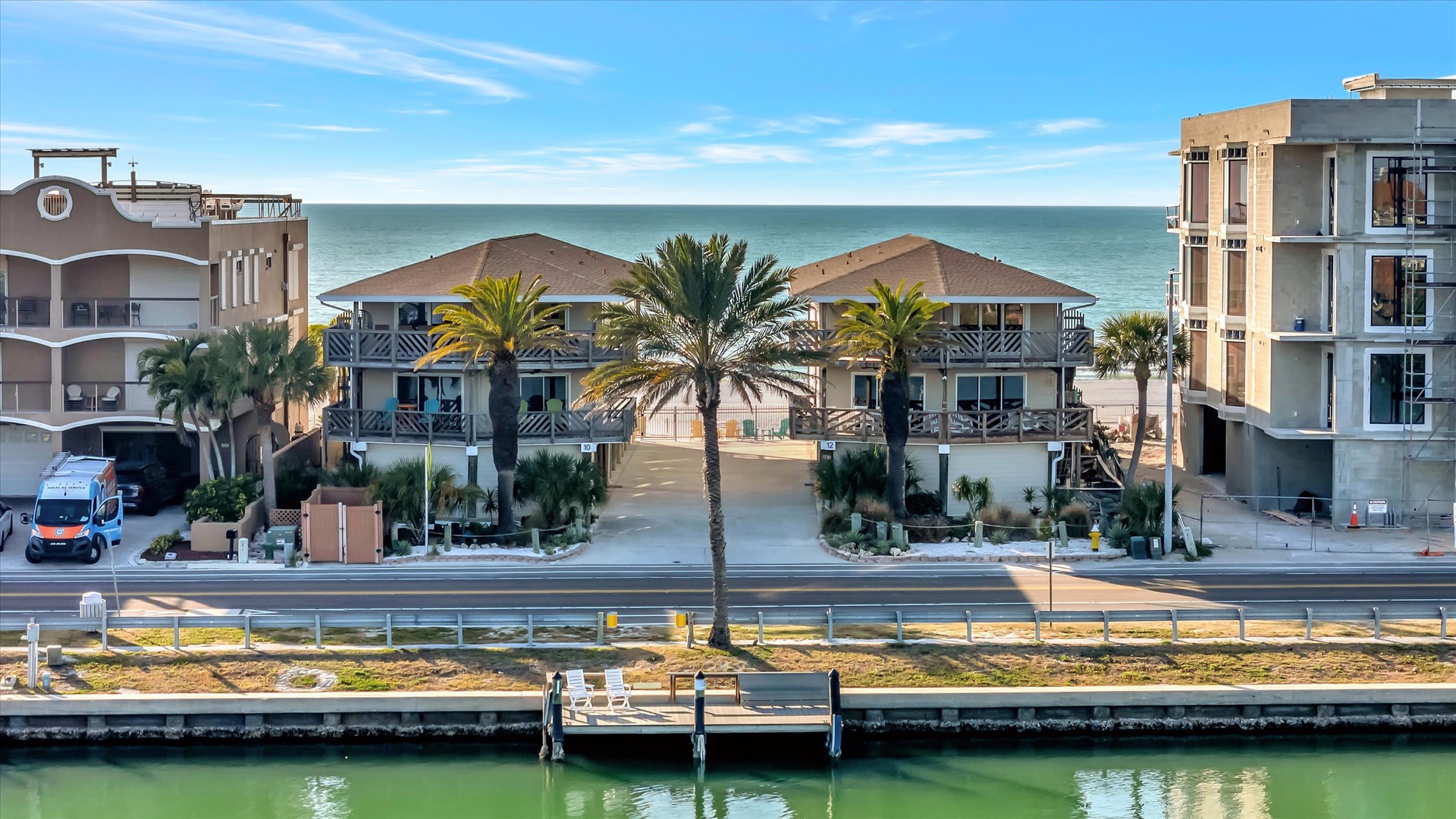 Waterfront property offering direct beach access with a private dock and stunning coastal surroundings. Palm trees frame the entrance while the turquoise ocean stretches along the horizon.