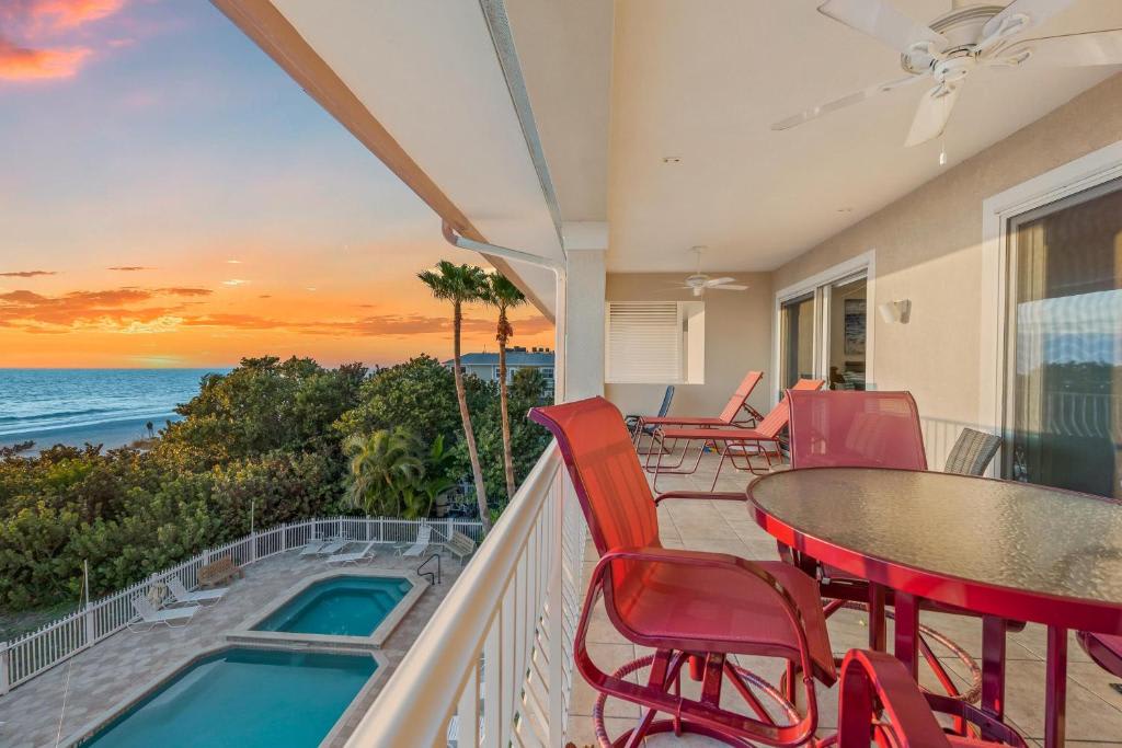 A spacious balcony with poolside seating showcases stunning sunset vistas over lush tropical greenery and sparkling ocean waters, creating your perfect evening retreat for unwinding after a day of exploration.