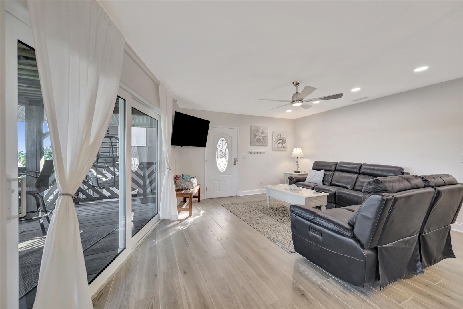 Step into your bright, open living space where comfortable leather seating invites you to unwind. Sheer curtains frame glass doors opening to your private deck, bringing natural light and an easy flow for indoor-outdoor living.
