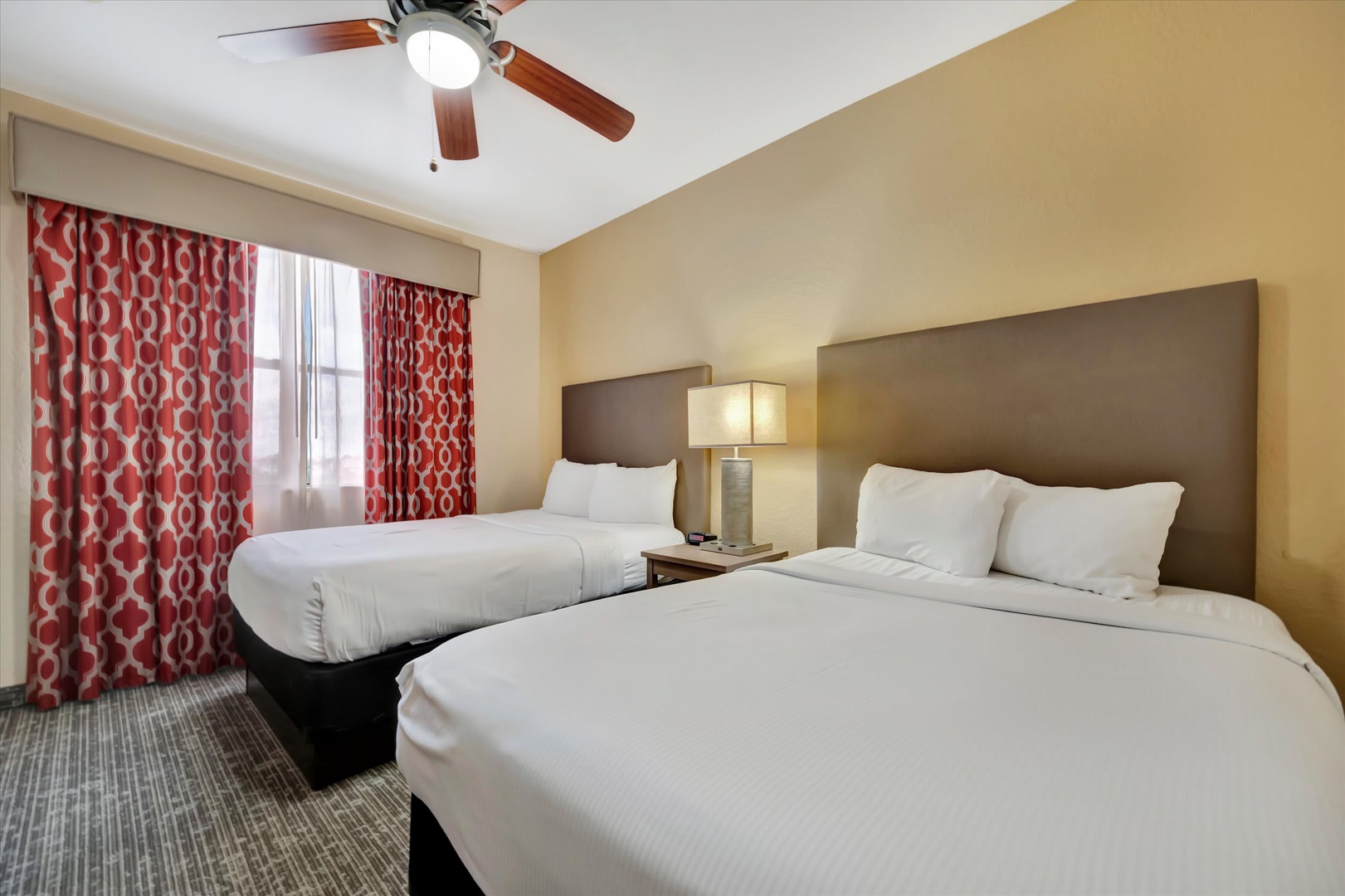 Slip into crisp linens and enjoy the gentle ceiling fan breeze after a day of exploring—your restful retreat awaits with two spacious beds and calming natural light.