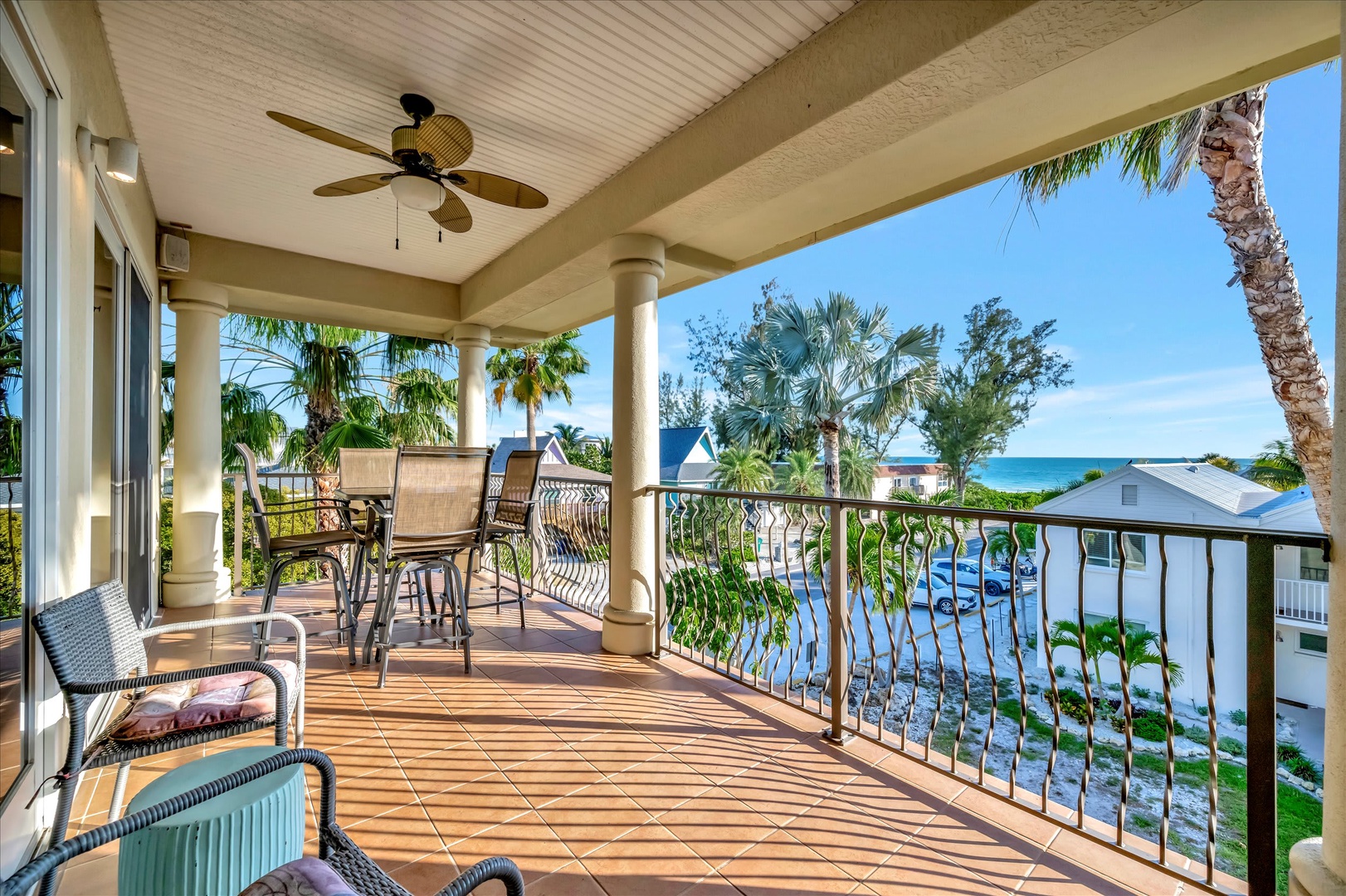 Your private balcony offers tropical breezes and stunning ocean views, with shaded seating perfect for morning coffee or sunset cocktails while palm trees sway in the distance.