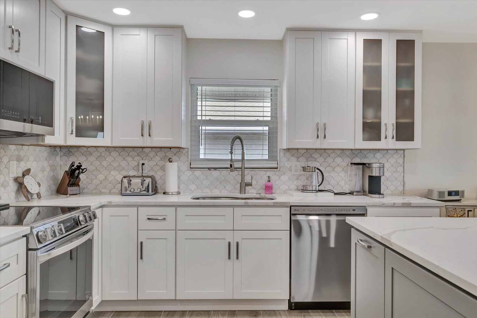 Cook your favorite meals in this bright, fully equipped kitchen with sleek white cabinetry, modern appliances, and elegant marble backsplash. Everything you need for a comfortable stay.