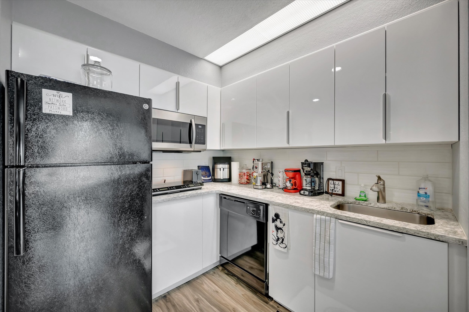 Step into your modern kitchen, where clean white cabinetry meets sleek stainless steel appliances. Bright under-cabinet lighting illuminates the marble countertops, perfect for preparing your morning coffee.