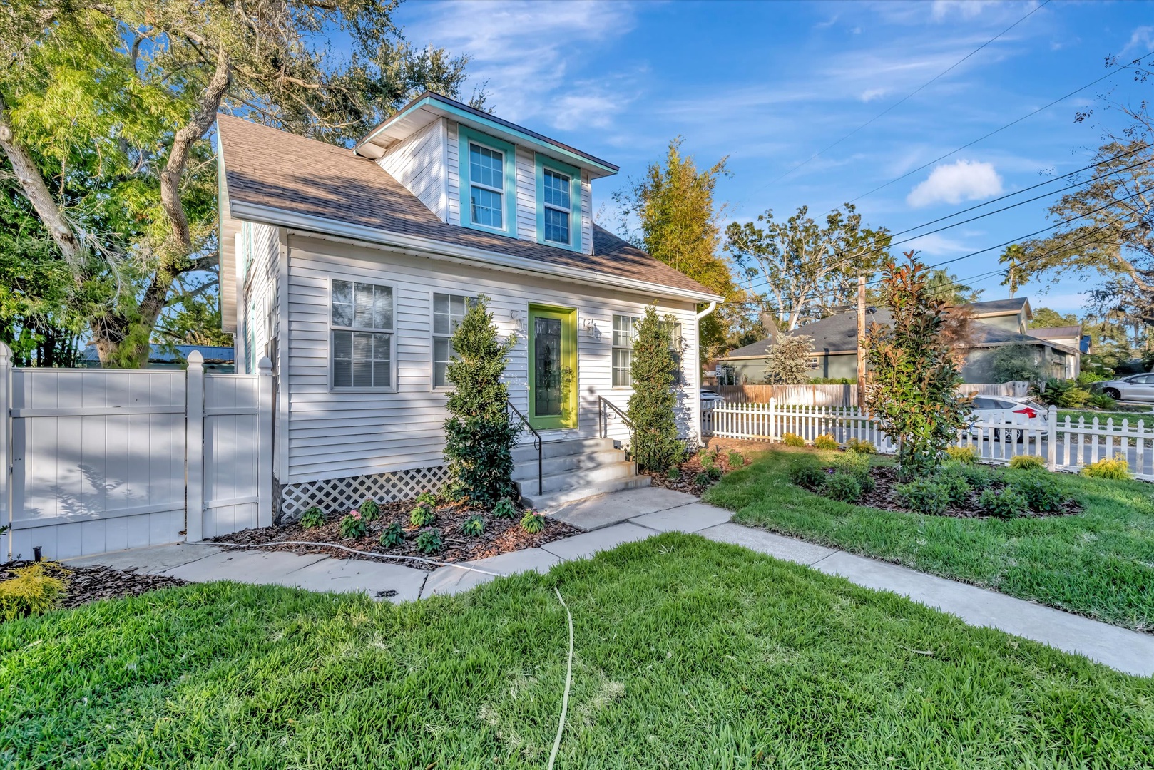 Charming cottage retreat with a cheerful yellow door welcomes guests to this peaceful residential neighborhood surrounded by lush greenery and autumn foliage.