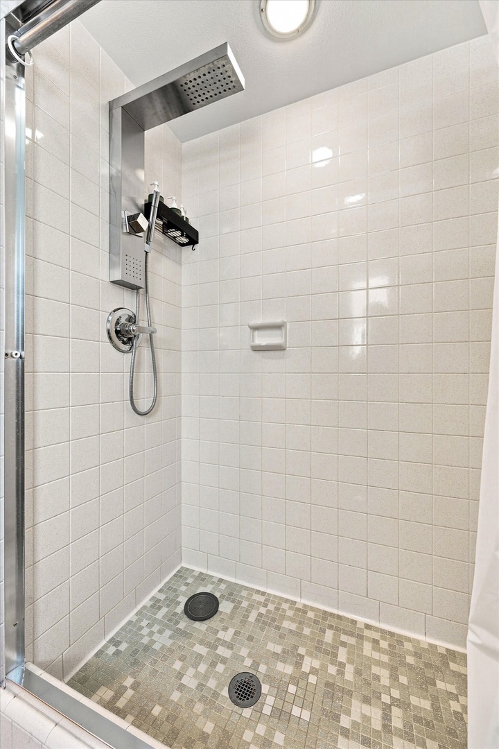 Rinse away the day under this modern rainfall showerhead, with sleek subway tile walls and a stylish mosaic floor that makes your morning routine feel like a spa escape.