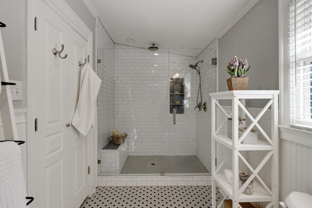 Your private spa-like bathroom features a spacious walk-in shower with dual showerheads, elegant subway tile, and a built-in bench. Fresh towels and thoughtful touches make this your perfect retreat.