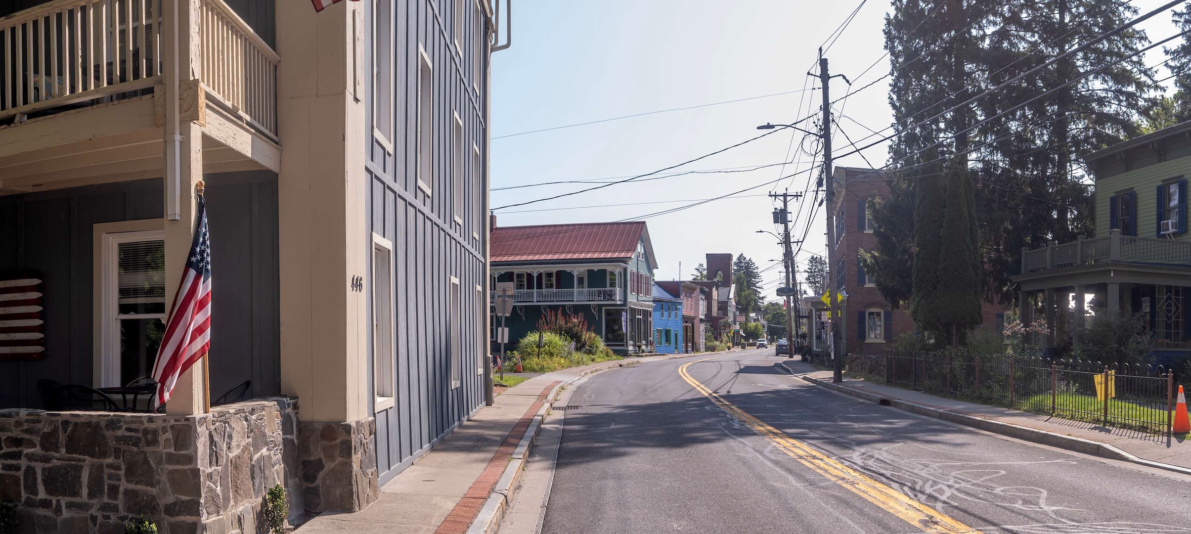 A charming small-town street scene with historic buildings, tree-lined sidewalks, and a peaceful roadway in the surrounding area.
