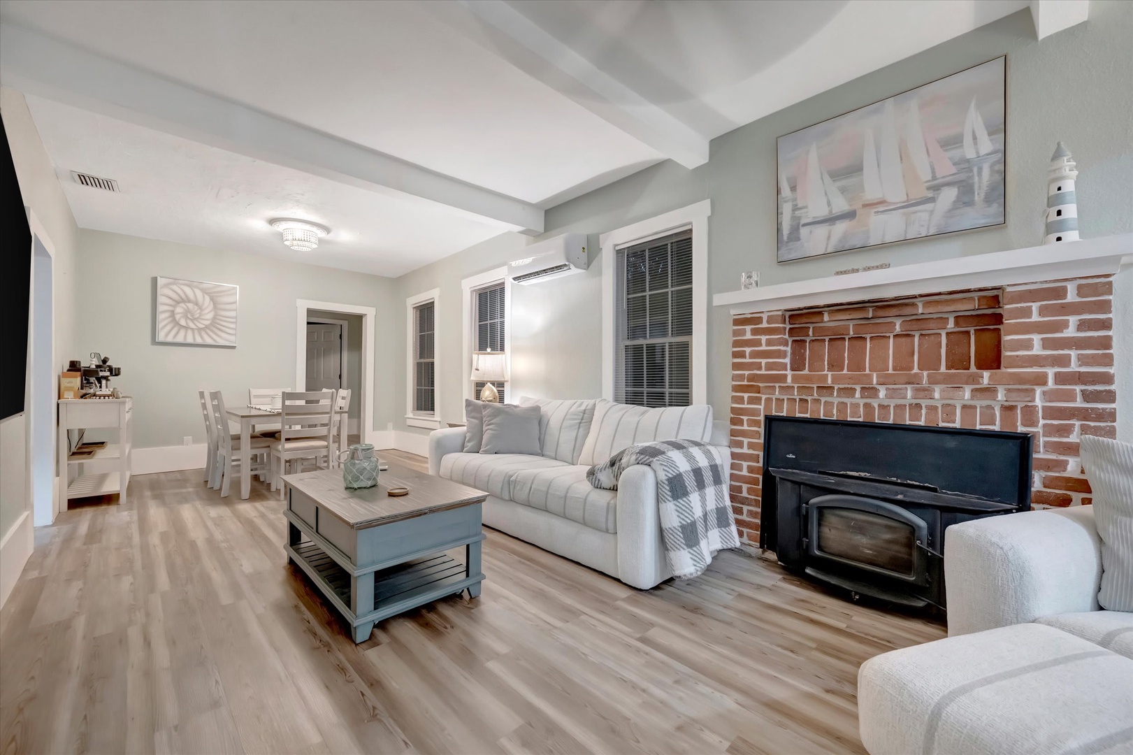 Settle into the plush sofa by the charming brick fireplace, where coastal touches and soft textures create your cozy home base for unwinding after each day's adventure.