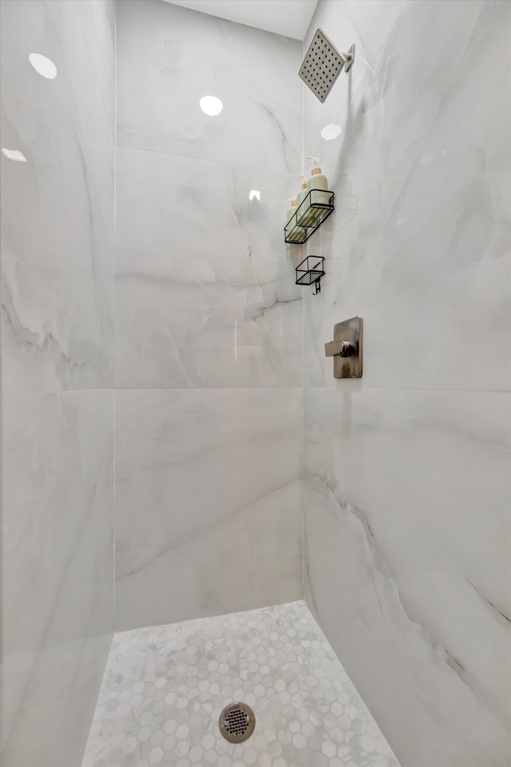 Step into your elegant marble-tiled walk-in shower, where a rainfall showerhead and modern fixtures create a spa-like retreat after a day of exploring.