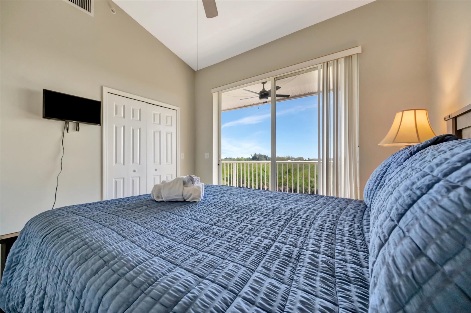 Wake up to natural light streaming through the balcony doors, framing your tranquil treetop view. Sink into the plush bed with fresh towels waiting, and unwind with your favorite shows on the wall-mounted TV.