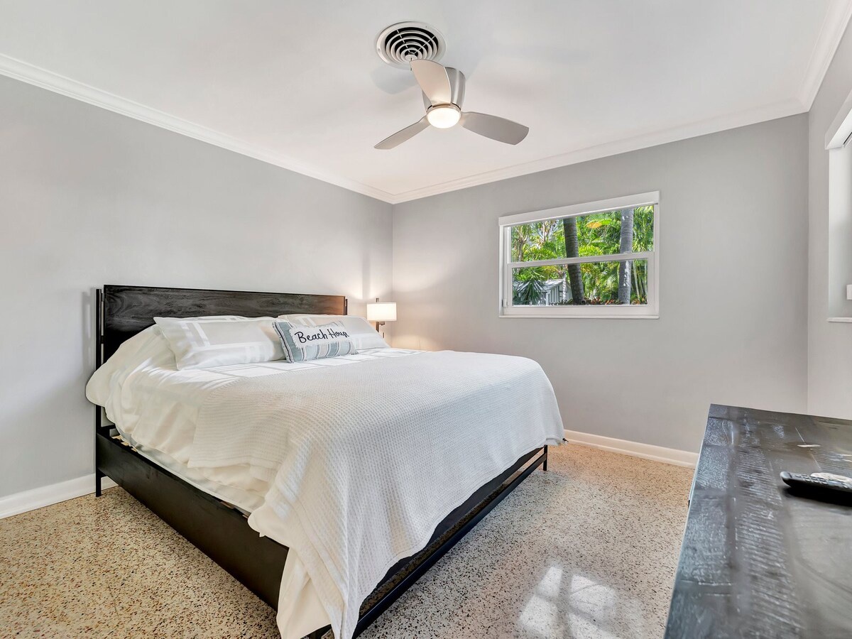 Slip into crisp white linens and let your worries drift away in this peaceful bedroom. A gentle breeze from the ceiling fan and a glimpse of tropical palms through the window set the tone for your relaxing escape.