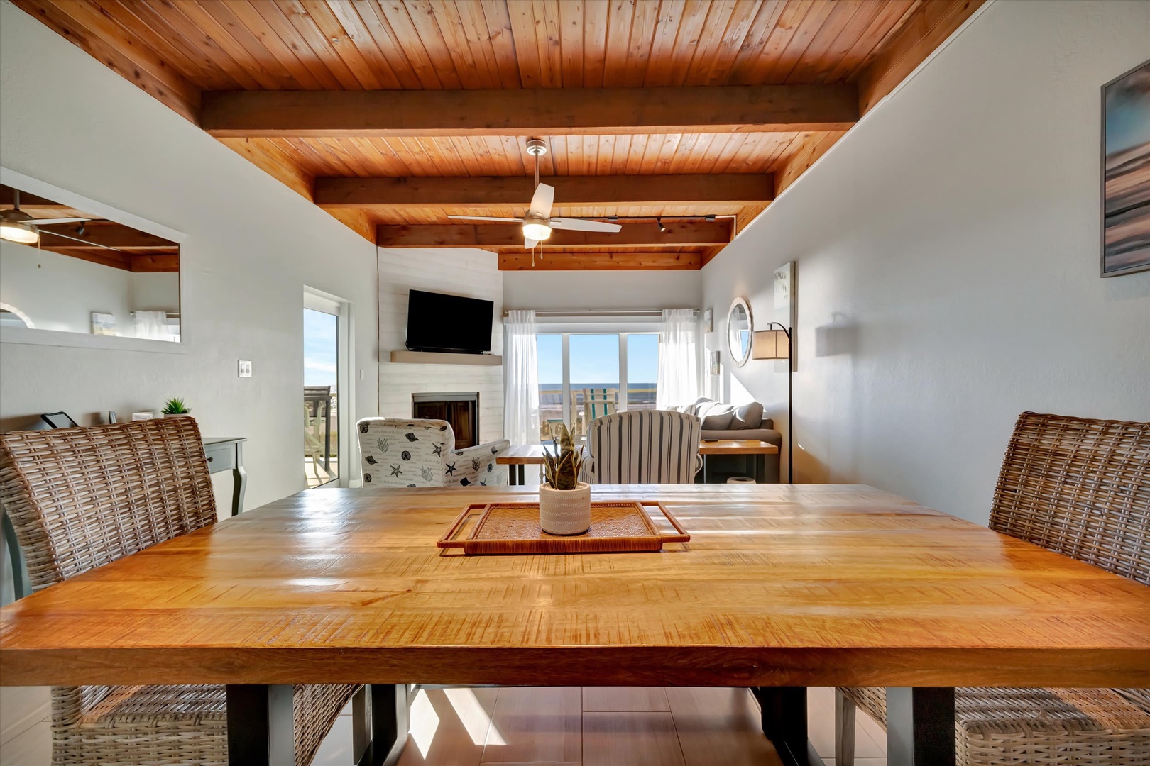 Gather around this handsome wood table beneath warm, natural beams—perfect for morning coffee or evening meals. Your ocean views and cozy fireplace set the scene for relaxed coastal living.