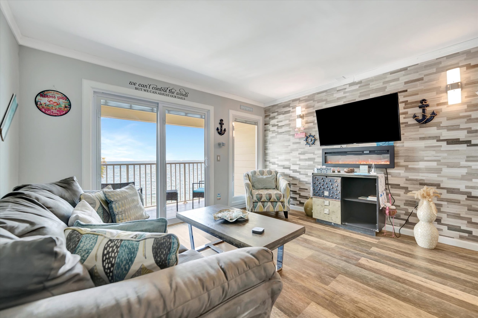 Unwind in this coastal-chic living room where nautical touches meet modern comfort. Through the glass doors, your private balcony frames an inviting water view—your perfect perch for morning coffee or sunset moments.