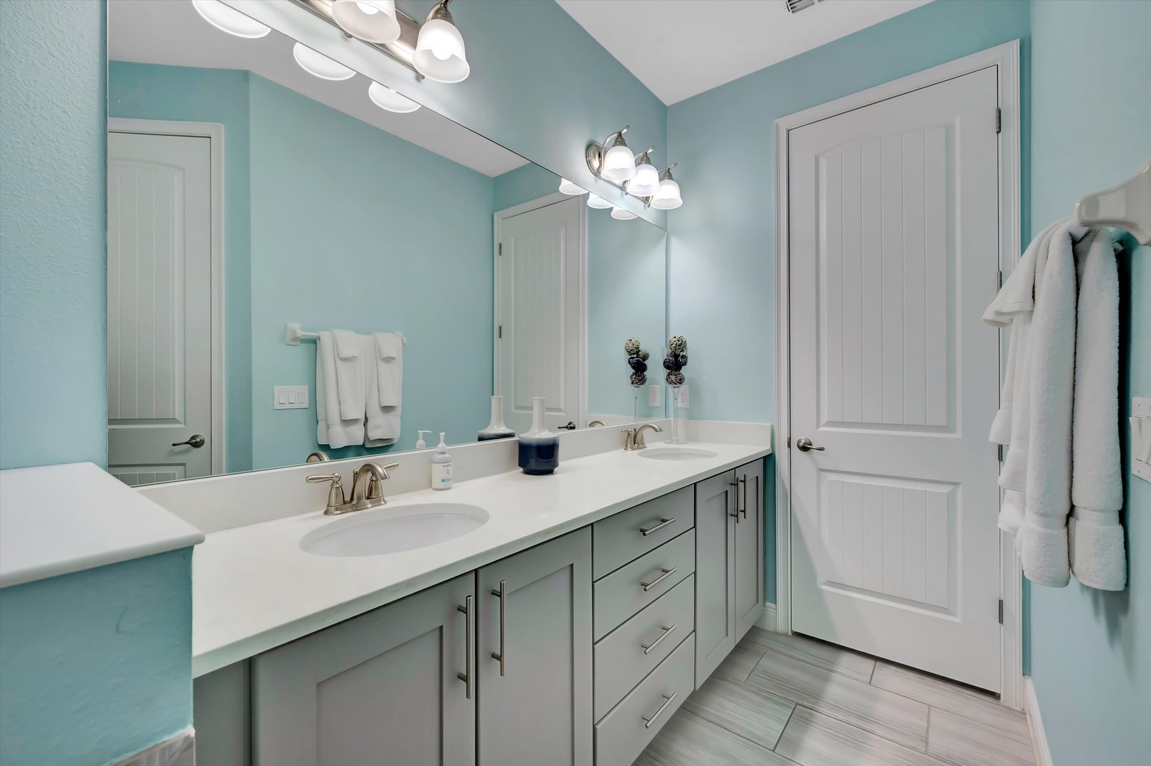 Refresh in your beautifully appointed bathroom, where soothing turquoise walls and a spacious dual-sink vanity create a serene spa-like retreat for your morning routine.