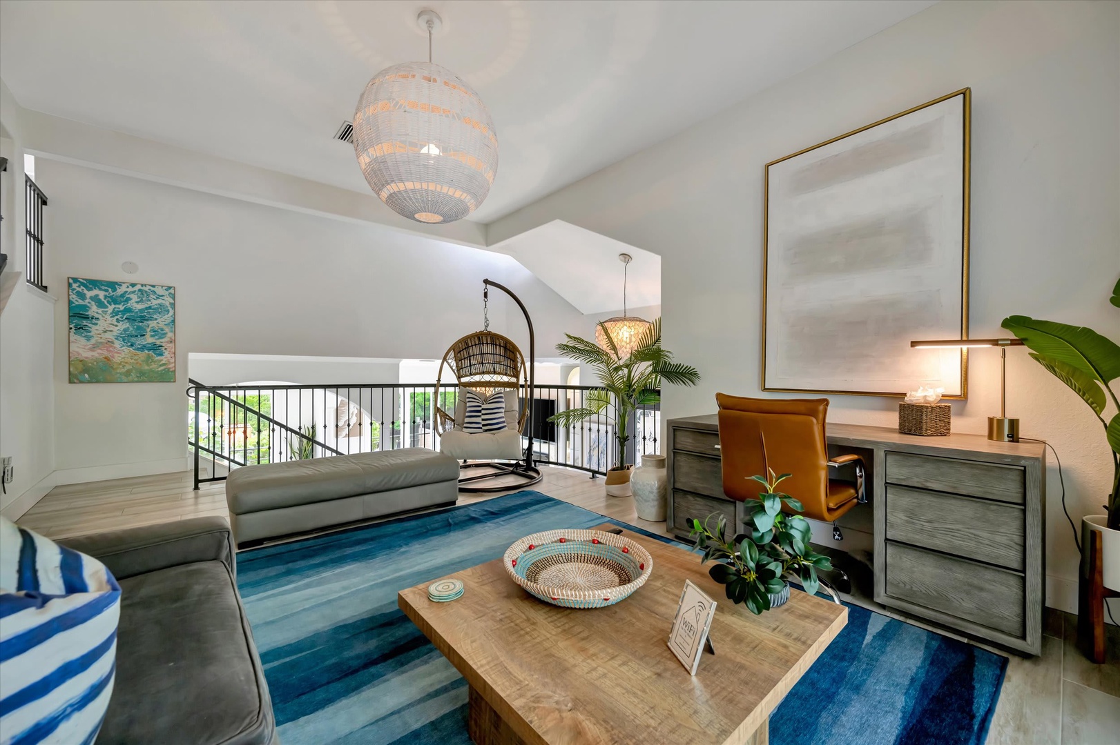 Sink into this airy loft living space, where coastal-inspired touches and soaring ceilings create your perfect retreat. The woven lighting and ocean-hued rug invite you to unwind in style.