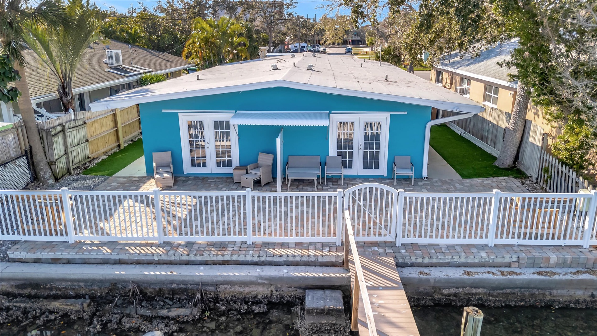 Charming waterfront property with direct dock access and a private backyard retreat featuring comfortable outdoor seating and tropical landscaping.