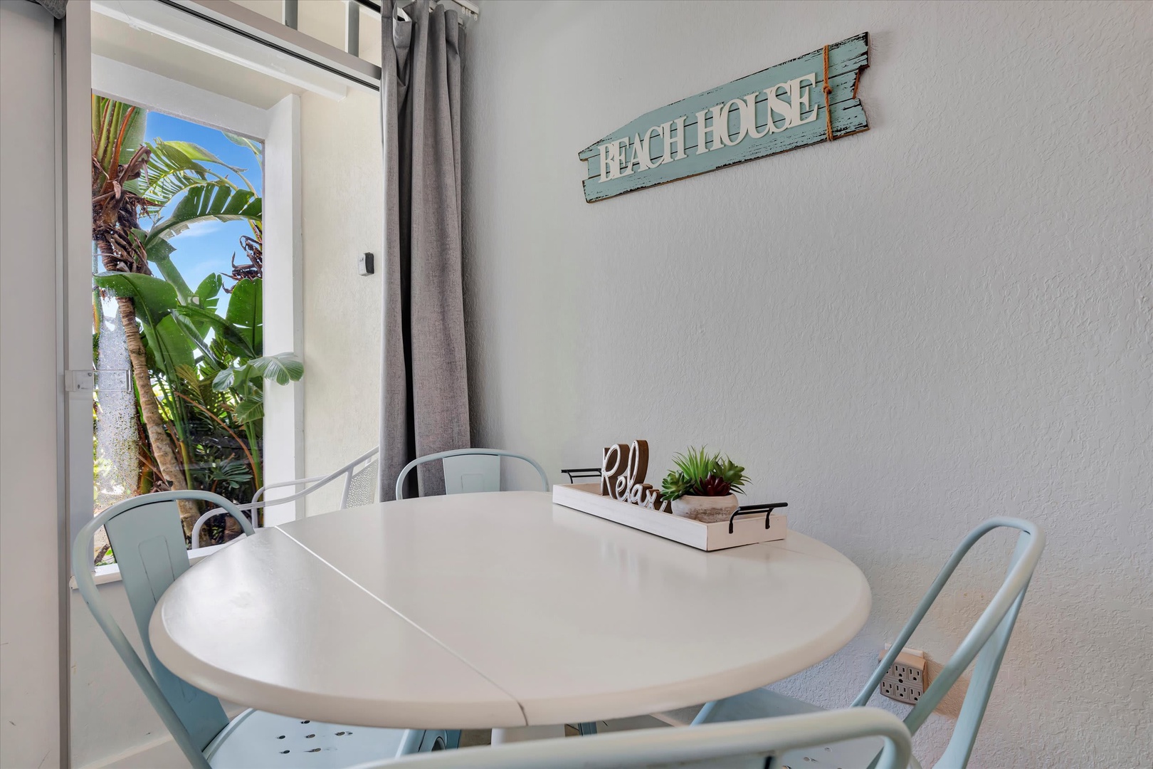 Step into your bright dining nook where beachy décor and light-filled tropical greenery just outside the door create a calm, coastal vibe. Enjoy morning coffee or a shared meal at your own welcoming table.