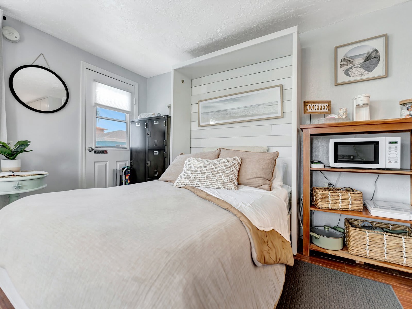 Slip into your cozy retreat with soft neutral tones and coastal accents. Your bed awaits beneath a charming shiplap accent wall, while thoughtful touches like fresh coffee and a beachy vibe make every morning feel special.