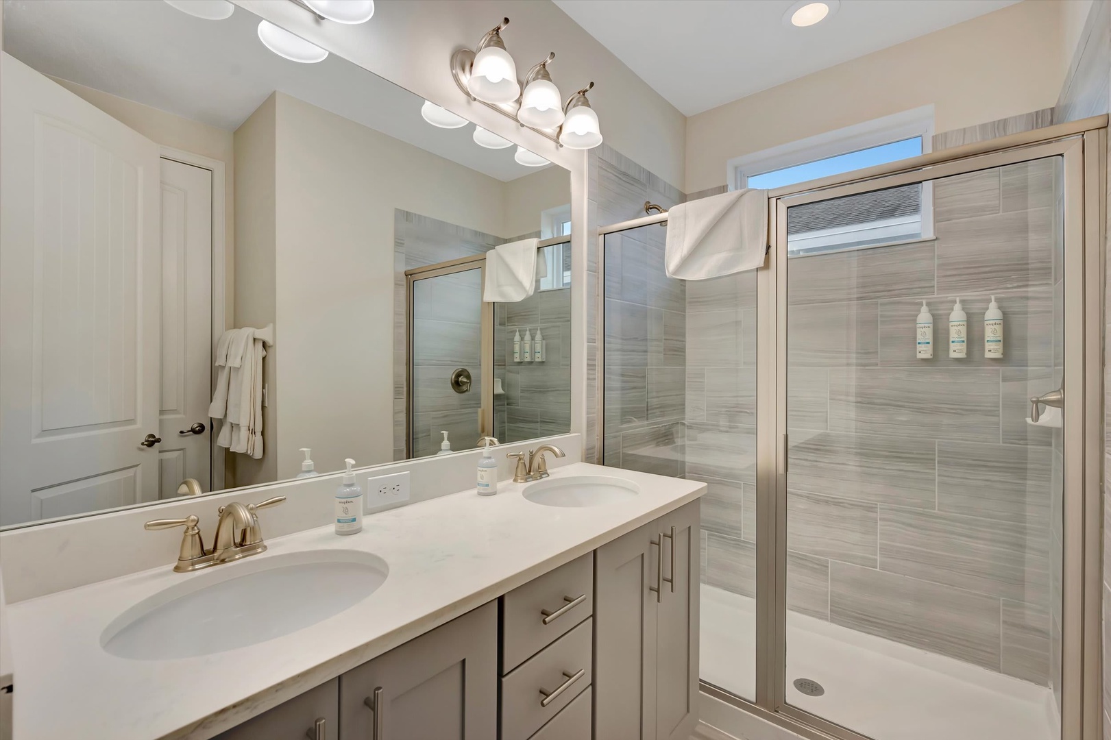 Step into this sleek, spa-inspired bathroom where modern elegance meets everyday comfort. Dual vanities with gold fixtures and a spacious walk-in shower with premium tile invite you to start and end your day feeling refreshed.