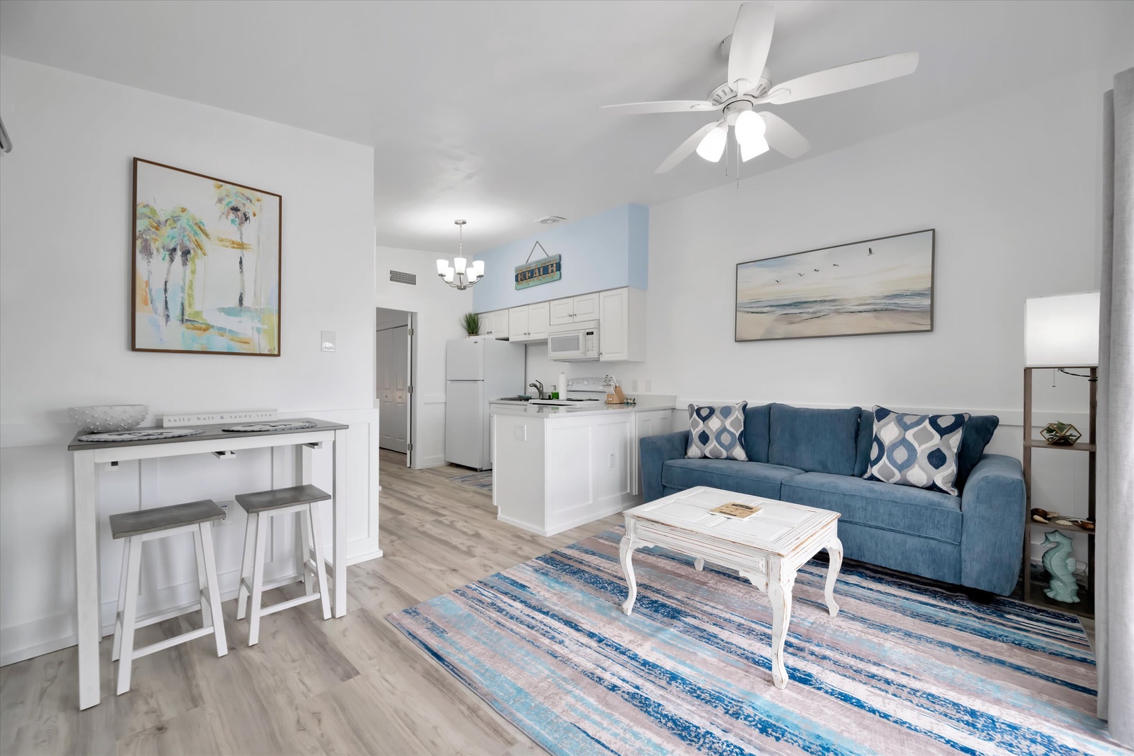 Step into your bright, open living space where coastal charm meets comfort. Relax on the plush blue sofa after a day of exploring, whip up meals in your fully-equipped kitchen, or enjoy a casual drink at the cozy breakfast bar.