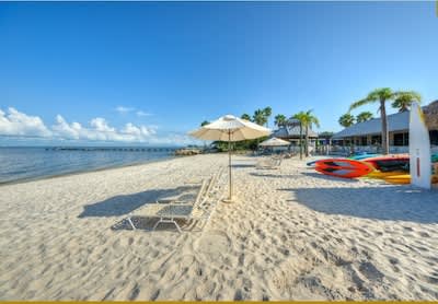 White sandy shores meet crystal-clear waters, framed by swaying palms and colorful kayaks waiting for adventure. Lounge under umbrellas while gentle waves and tropical breezes set the scene for your perfect beach escape.