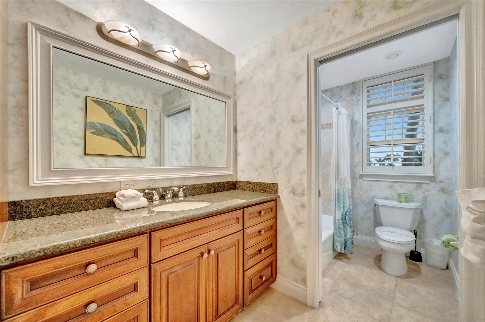 Step into your elegant bathroom with warm wood cabinetry, granite countertops, and soft natural light. A relaxing tub awaits your arrival.
