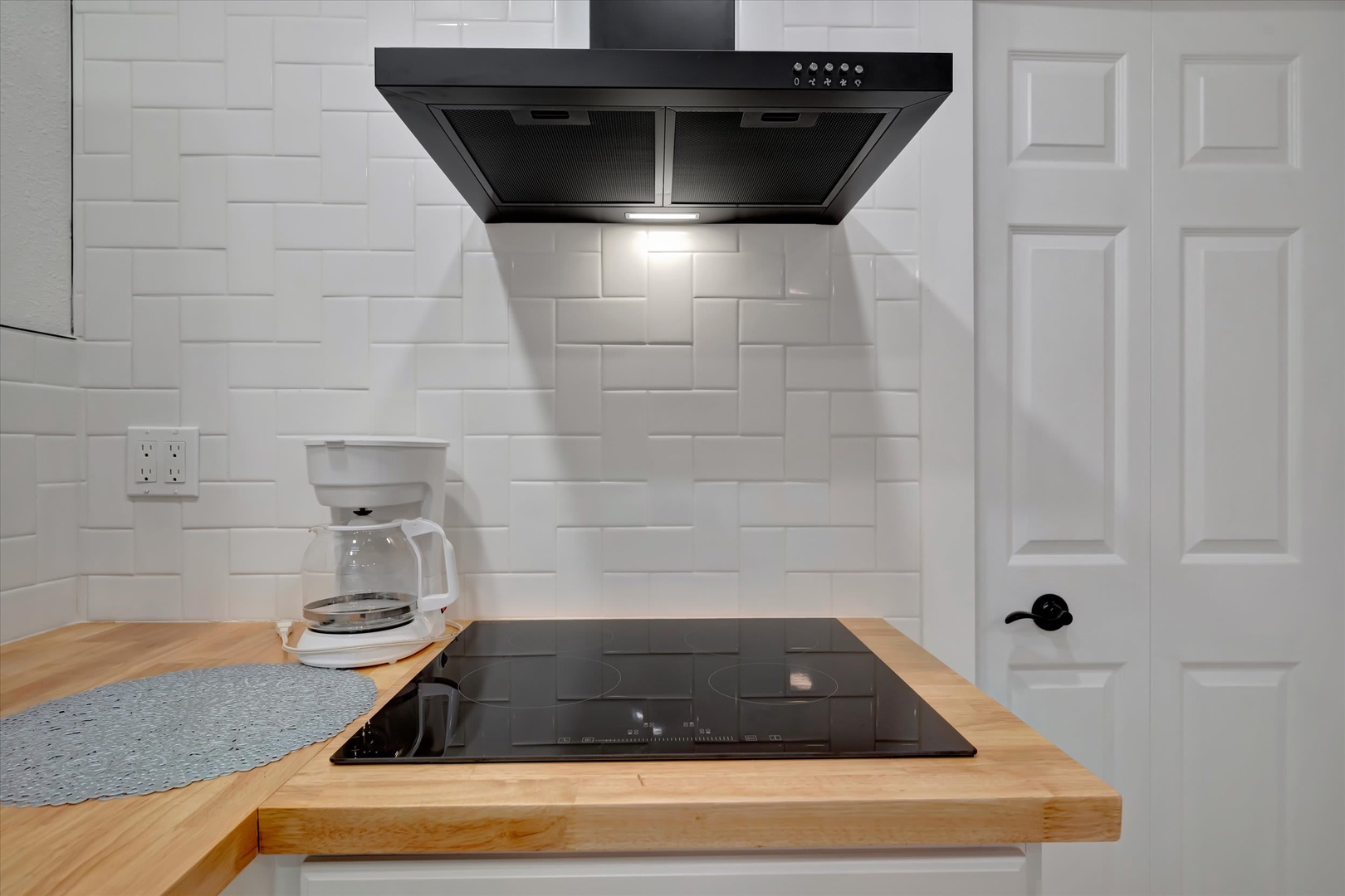 Your fully equipped kitchen features sleek butcher block countertops, a modern induction cooktop, and fresh white subway tile backsplash—perfect for preparing morning coffee or a home-cooked meal during your stay.