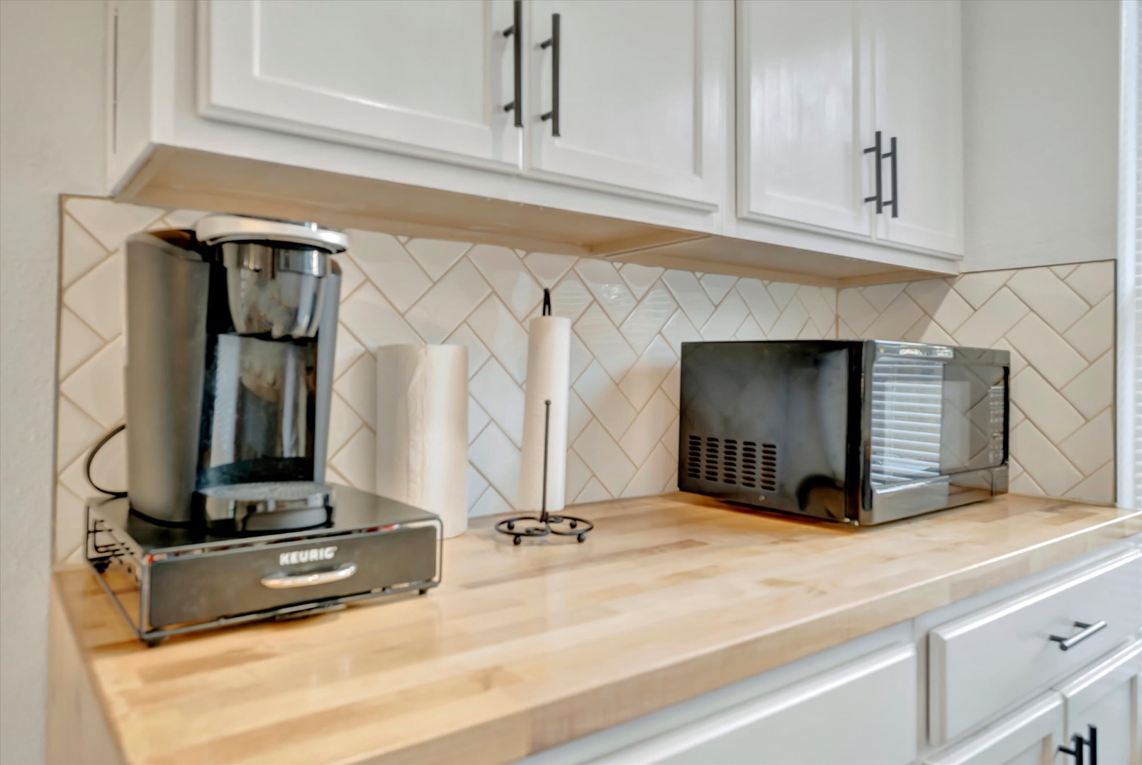 Your bright kitchen features warm wood countertops, stylish herringbone tile backsplash, and modern appliances ready for your morning coffee routine.
