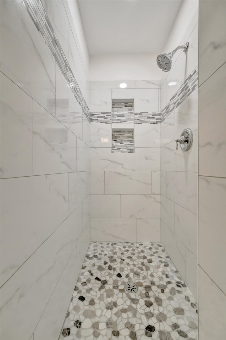 Step into your spa-like shower, where marble-style walls meet river rock flooring beneath a refreshing rainfall showerhead—your own private retreat after a day of adventure.