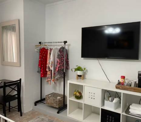 Your cozy living space with a mounted TV, open shelving for your essentials, and a convenient clothing rack—everything you need to settle in and feel at home.