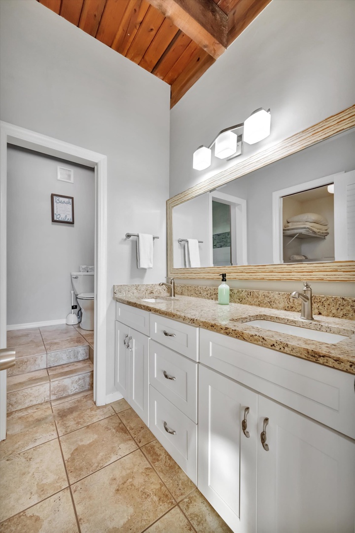This inviting bathroom features dual vanities with elegant granite countertops and vaulted wood ceilings that create an airy, spacious feel for your morning routine.