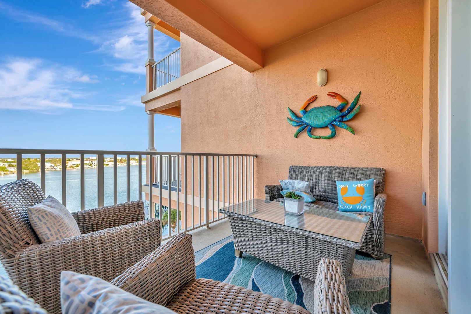 Your private waterfront balcony invites you to relax in wicker seating, sip your morning coffee, and soak in serene water views framed by cheerful coastal charm.