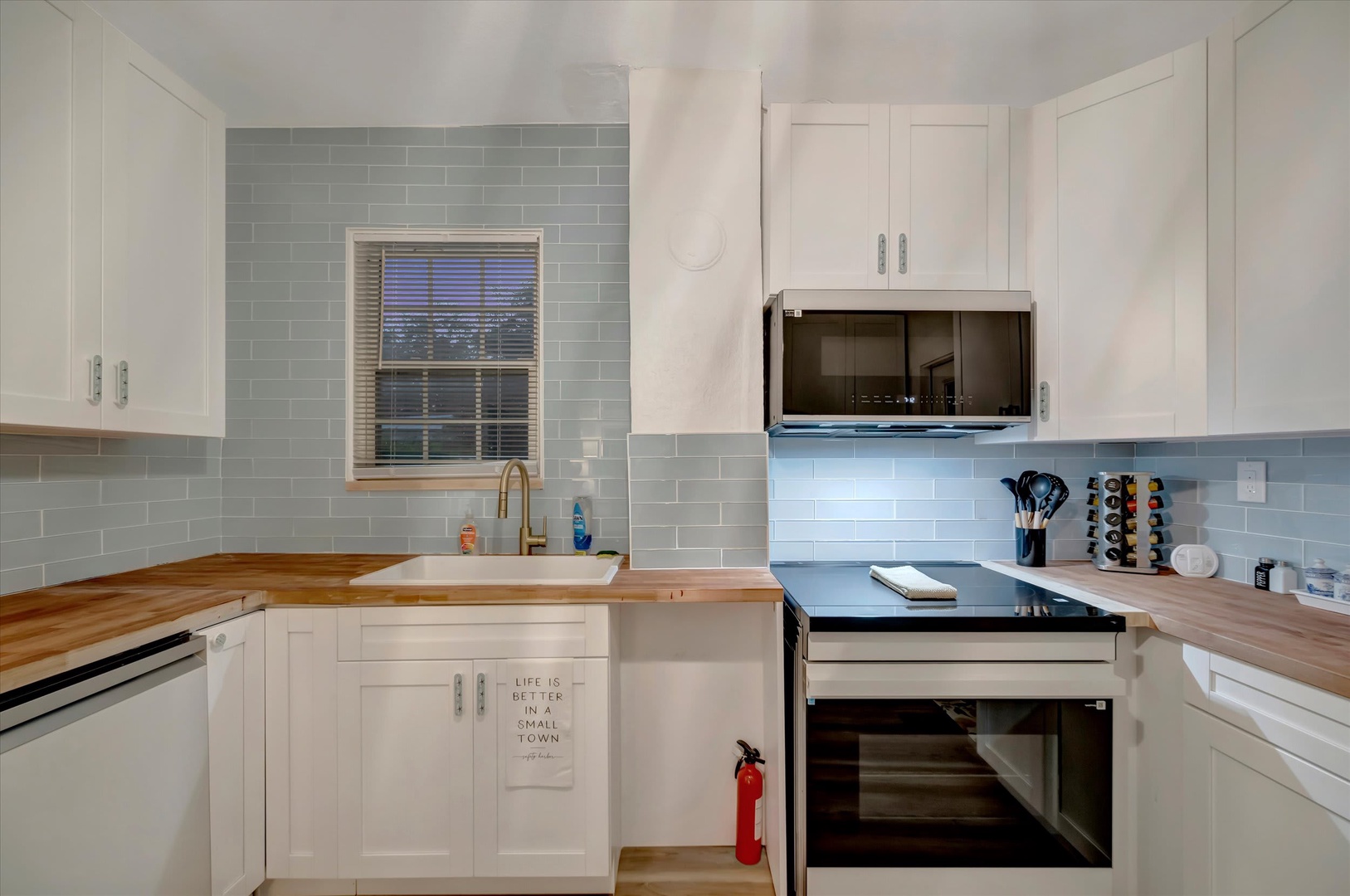 This beautifully updated kitchen features soft blue subway tile, warm butcher-block counters, and modern appliances—everything you need to whip up your favorite meals during your stay.