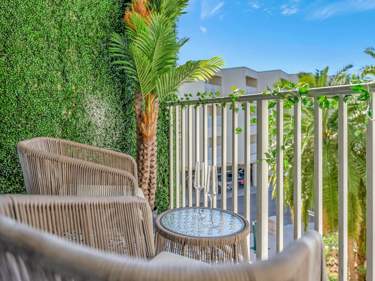 This is the view from your private balcony, where you can unwind among lush greenery and tropical palms. The inviting railing and comfortable seating create your perfect spot to sip morning coffee or enjoy an evening drink under the open sky.