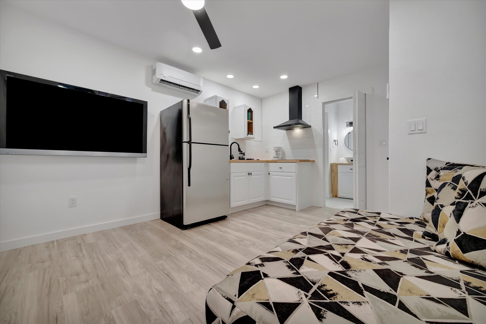 Your modern studio features a sleek kitchen with white cabinetry and wood countertops, plus climate-controlled comfort with efficient air conditioning overhead.