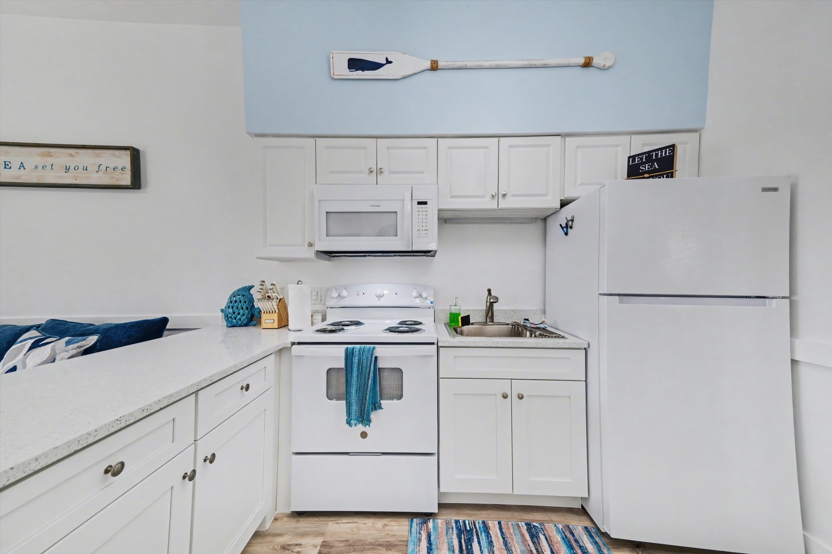 Your coastal-inspired kitchen awaits, complete with everything you need to whip up vacation meals—full stove, microwave, refrigerator, and charming nautical touches throughout.