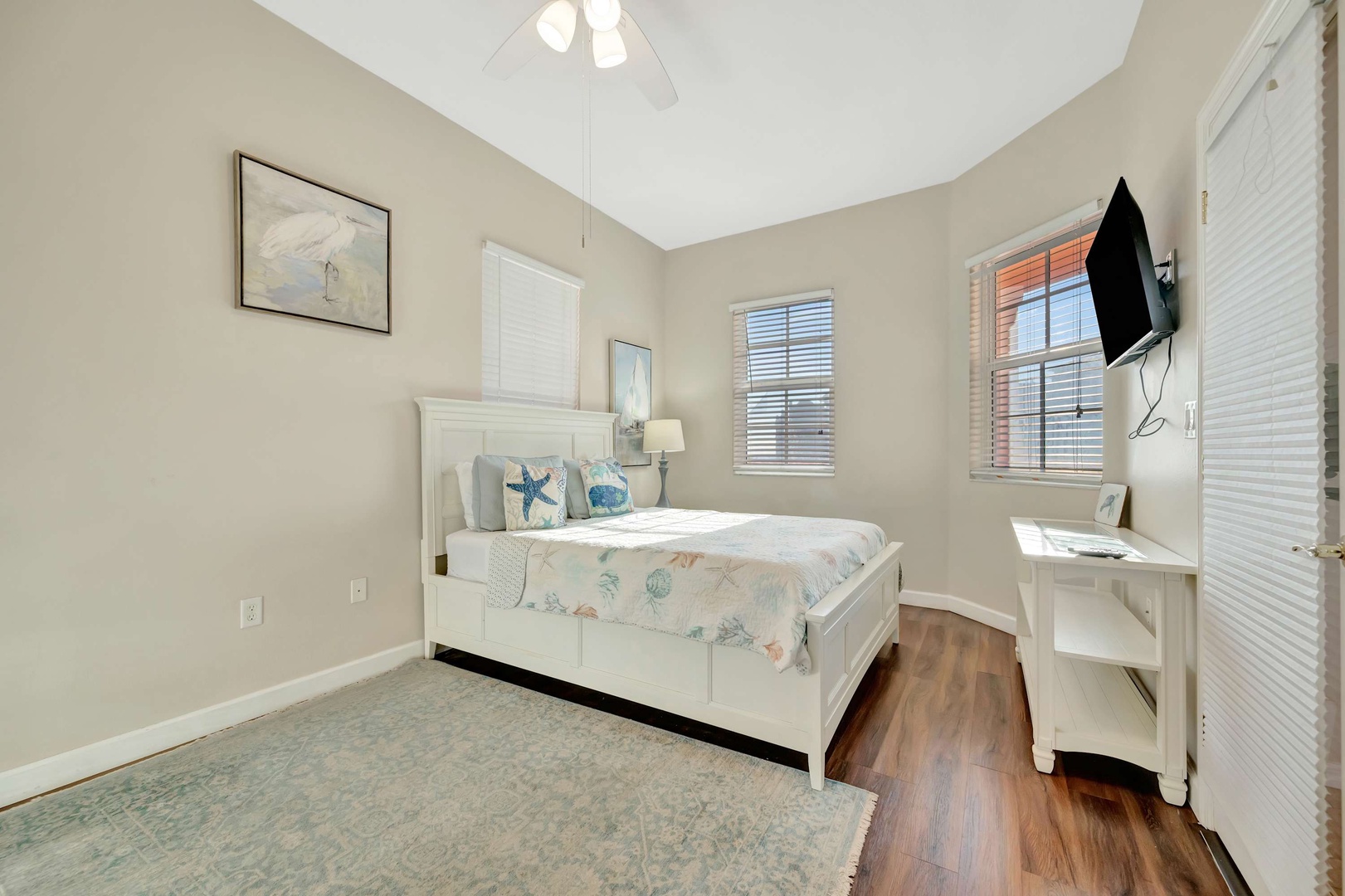 Drift off in this peaceful bedroom with coastal-inspired touches, vaulted ceilings, and warm natural light streaming through the windows. Your comfort awaits in a serene, restful space.