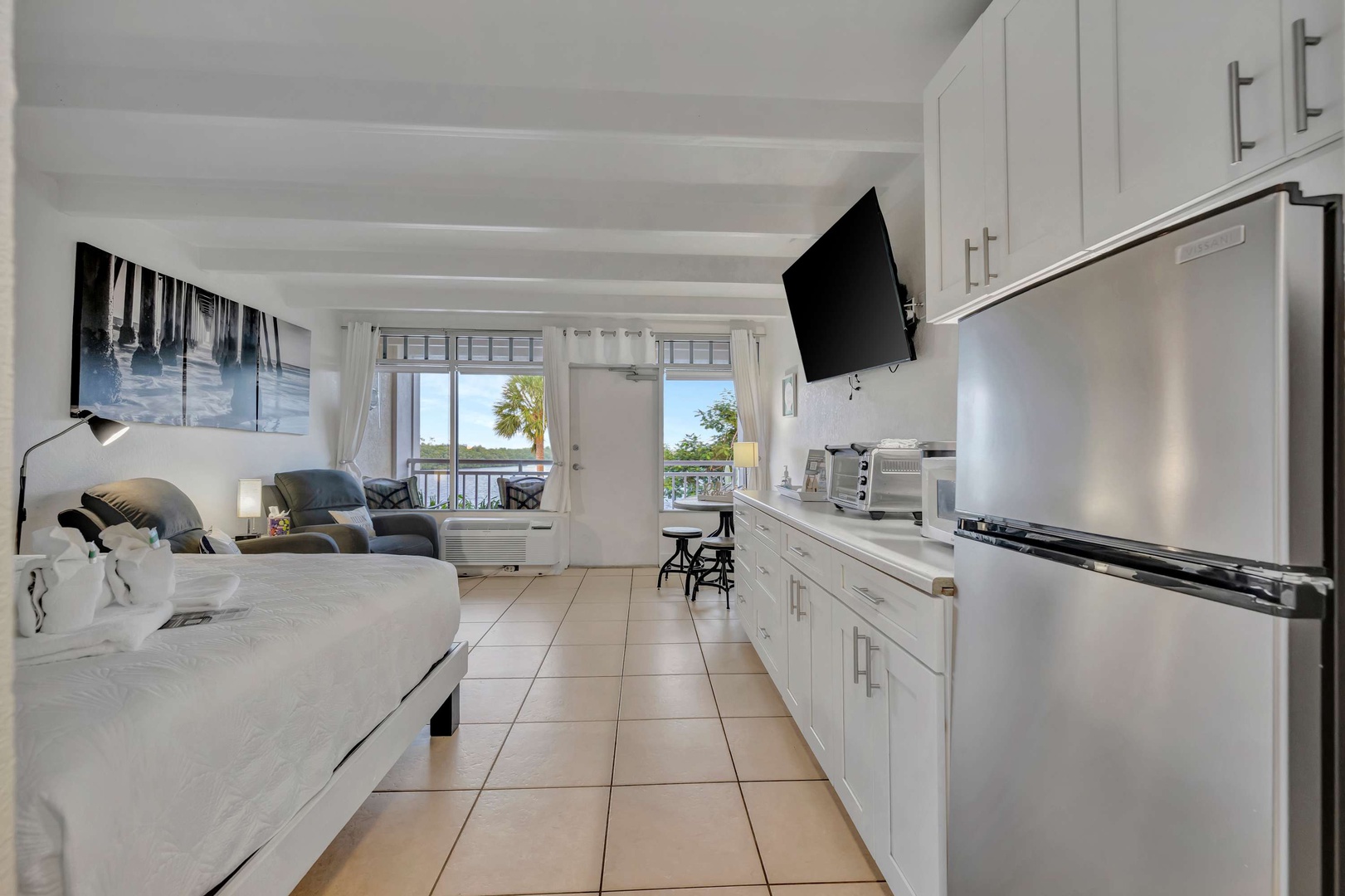 Step into your bright, breezy coastal retreat. The open layout flows from kitchen to living space, where palm-fringed views welcome you through the balcony doors—perfect for lazy mornings or sunset cocktails.