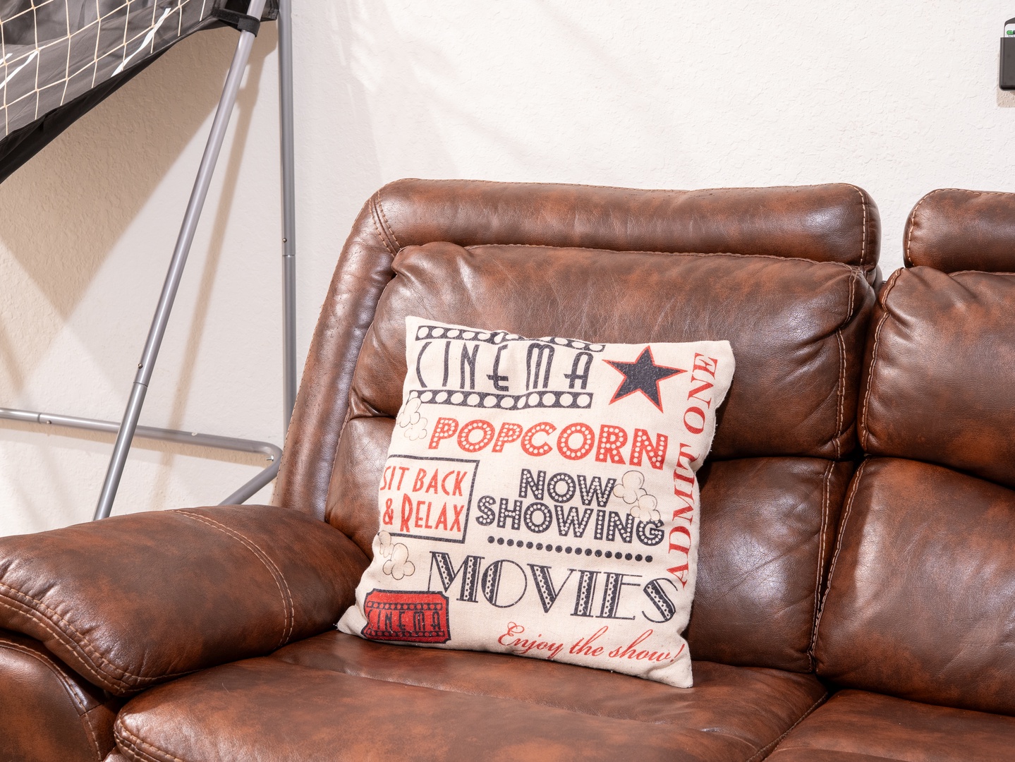 Sink into this rich leather sofa and let your vacation begin. The cozy texture and nostalgic movie-themed accent pillow make this the perfect spot for your downtime.
