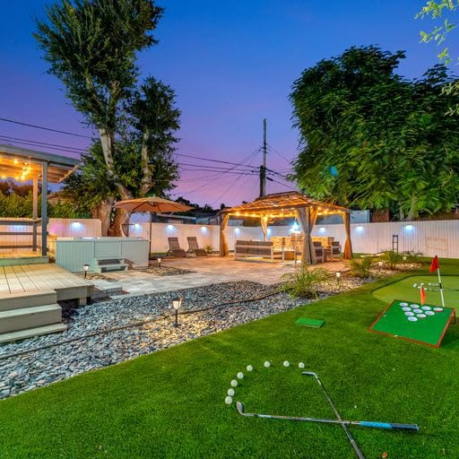 This beautifully lit backyard offers everything you need for evening relaxation and play. Enjoy games on the artificial turf, unwind under the covered patio, or soak in the ambiance as twilight sets in.