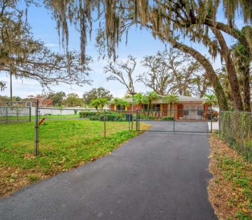 The property entrance sits on peaceful grounds framed by stunning old-growth trees draped with Spanish moss, setting the scene for a serene Southern retreat.
