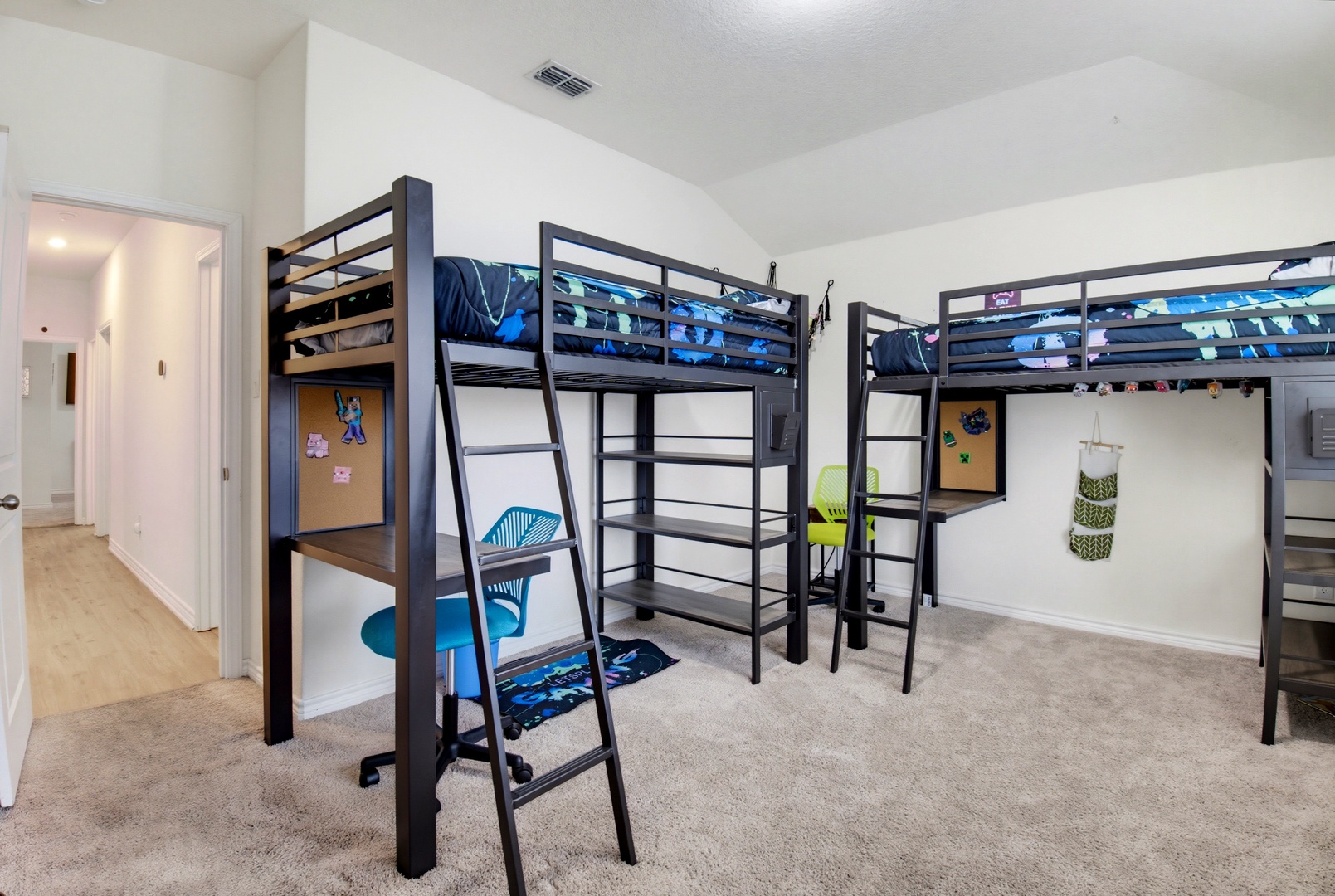 A bright, spacious bedroom featuring two loft beds with study desks below, offering your kids the perfect balance of play, sleep, and homework space under one high ceiling.